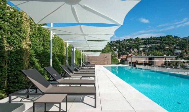 Image of the swimming pool and sunloungers and umbrellas outside the hotel
