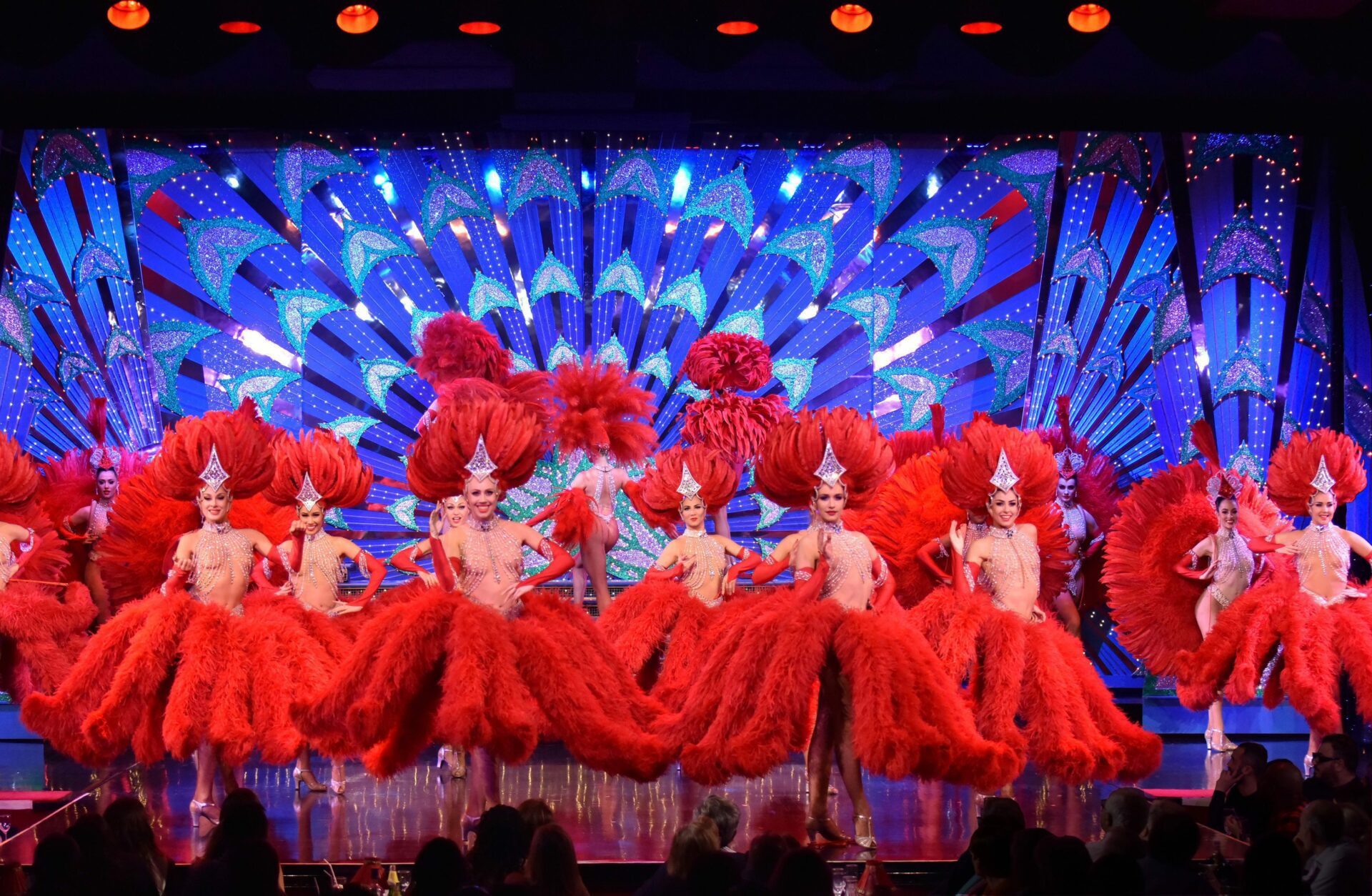 Dancers performing in red dresses with feathers on stage
