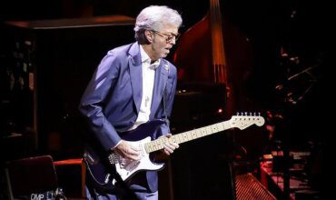 Eric Clapton playing guitar in darkened setting